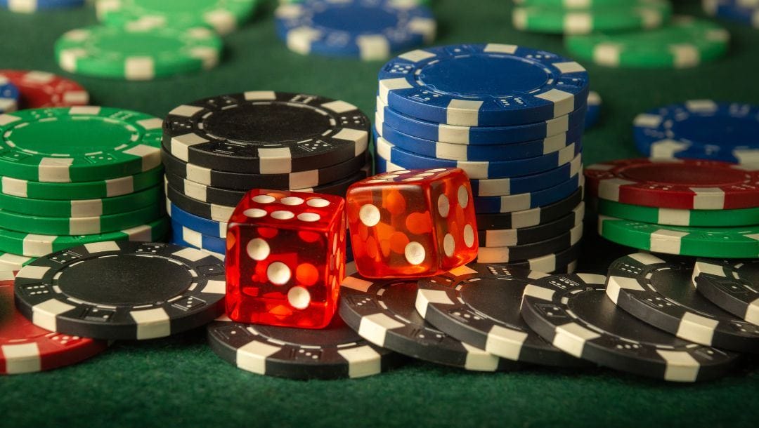 two red six-sided dice on top of poker chips on a green felt poker surface
