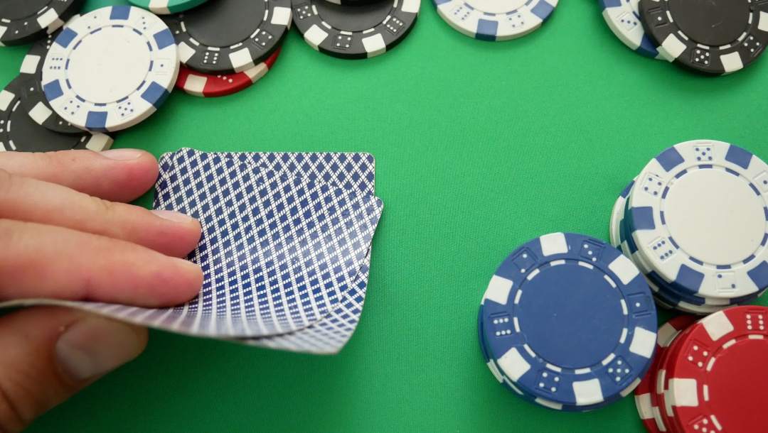 A poker looks at their hand with poker chips on the table