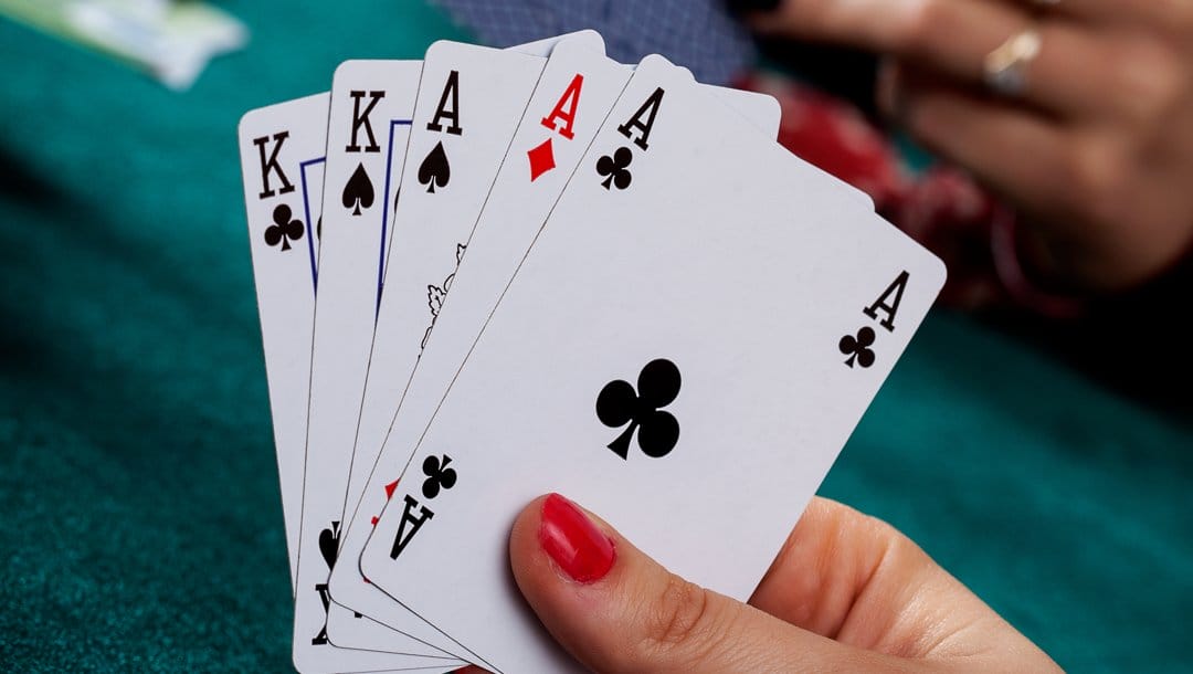 A poker player looks at their full house hand. It consists of two kings and three aces.