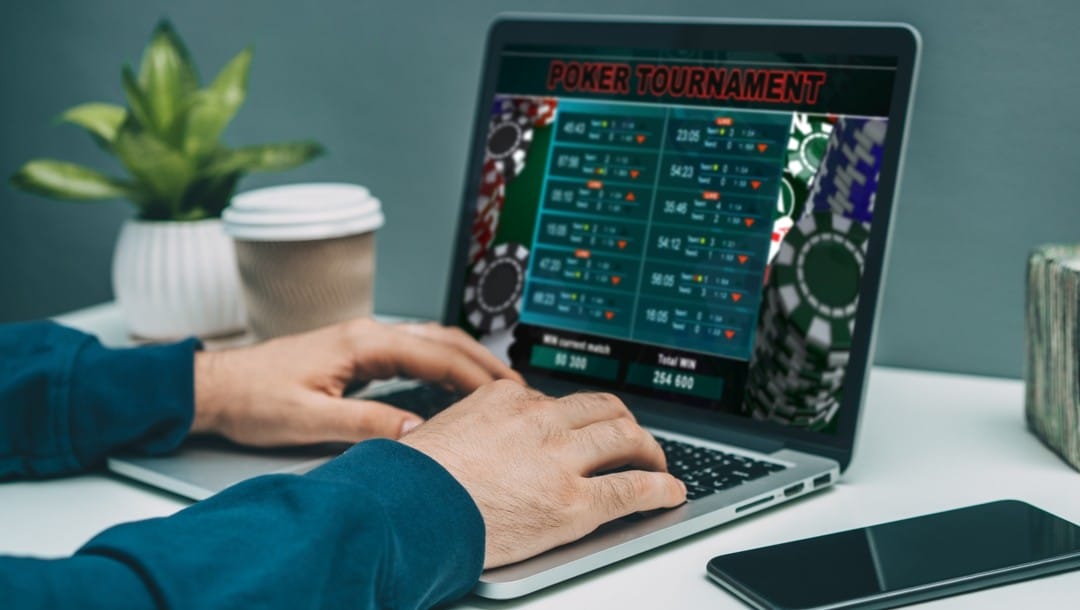 A pair of hands type on a laptop keyboard, ‘poker tournament’ appears on the laptop screen