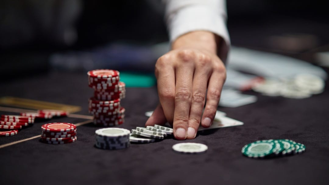 A croupier pushes forwards poker chips on a table