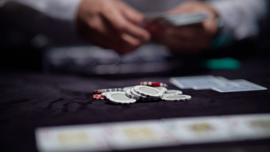 focus is on a pile of poker chips on a gambling table with a dealer blurred in background