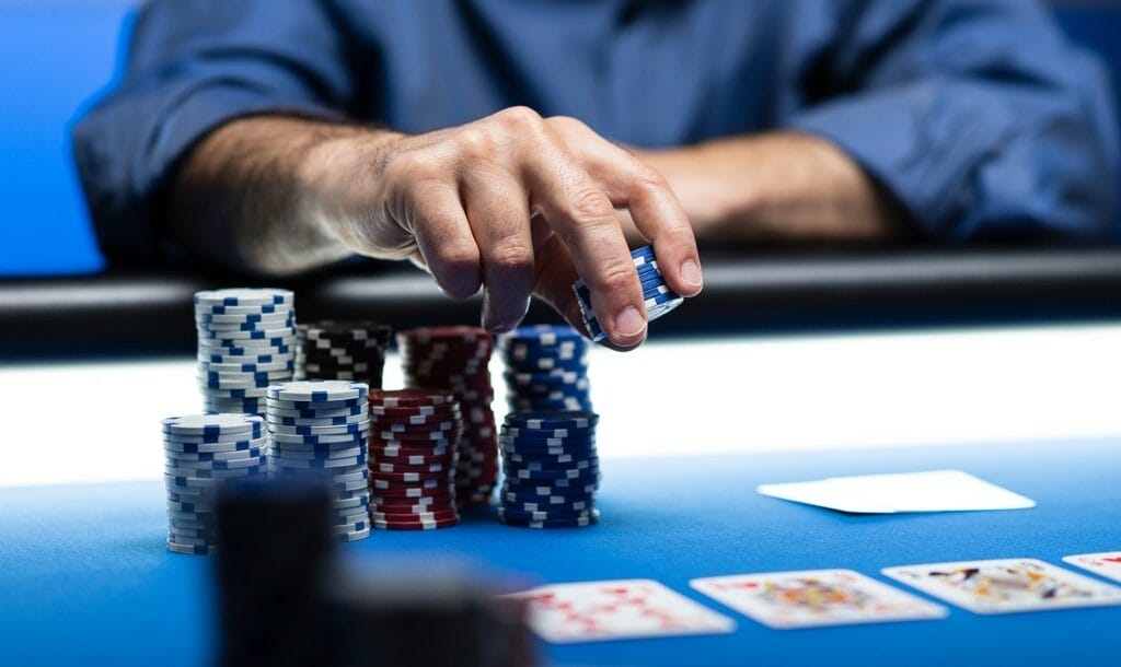 Player betting chips at casino, with poker cards on the table