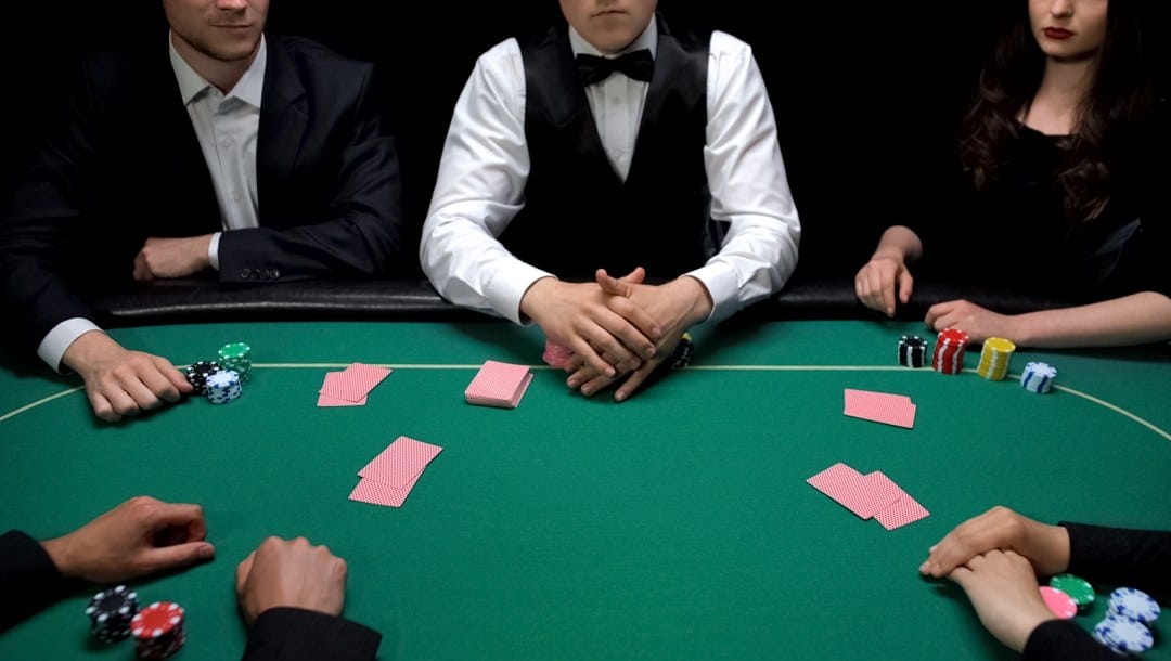 Players sit ready at start of poker game at green table
