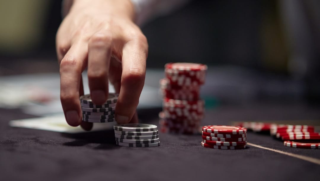 Dealer or croupier shuffles poker cards in a casino on the background of a table, chips