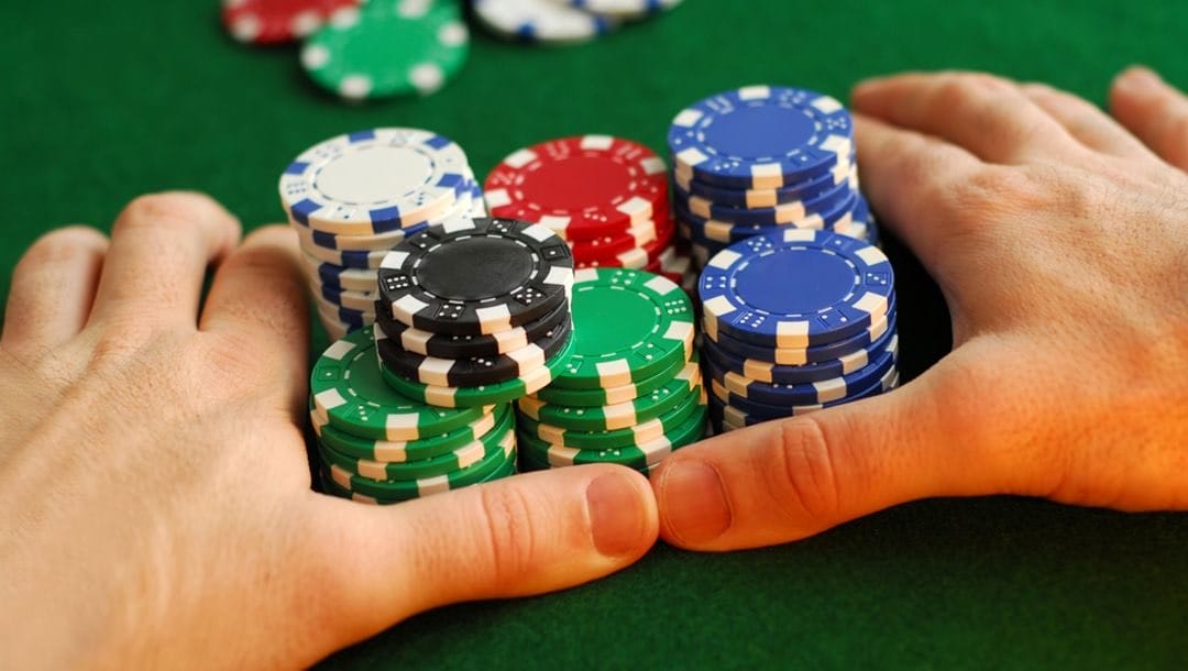 A poker player pushing all their chips towards the dealer.