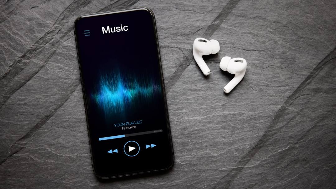 A smartphone with a music app open near to some earphones