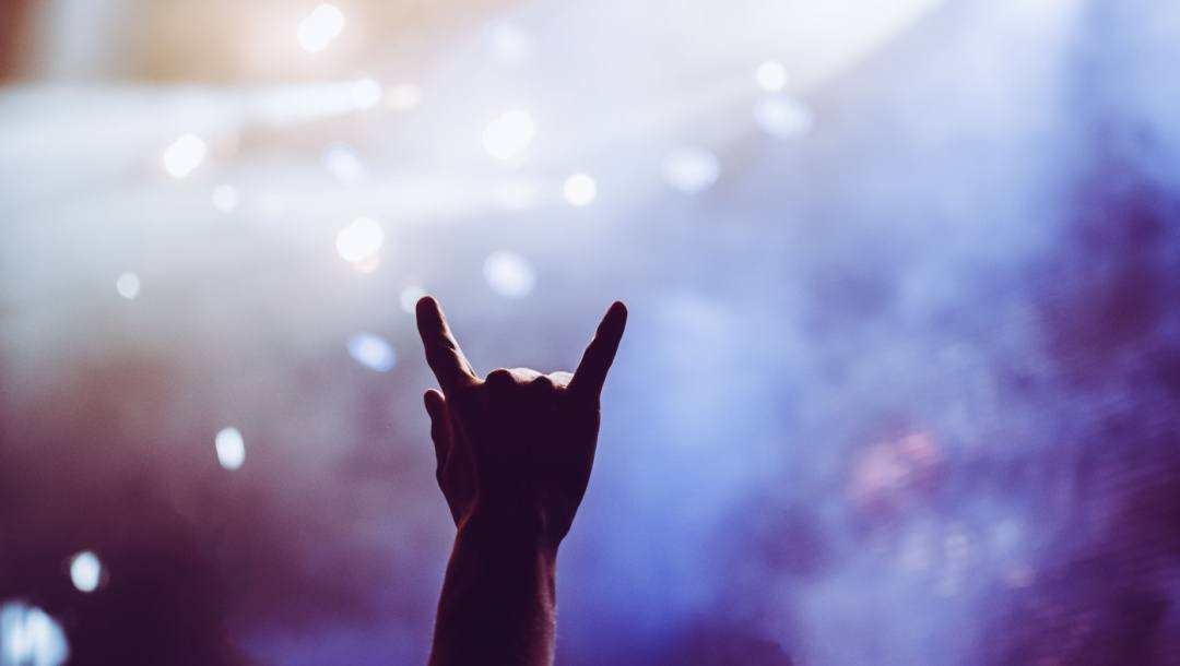 A person holds up a rock ’n’ roll hand sign during a concert