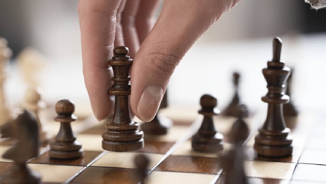 A person picking up a chess piece