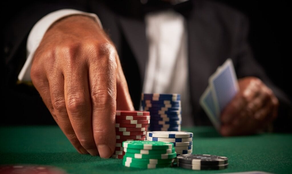 A hand places poker chips on a poker table
