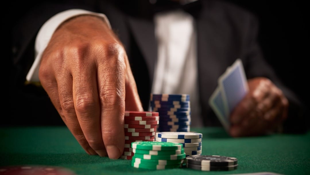 A hand places poker chips on a poker table