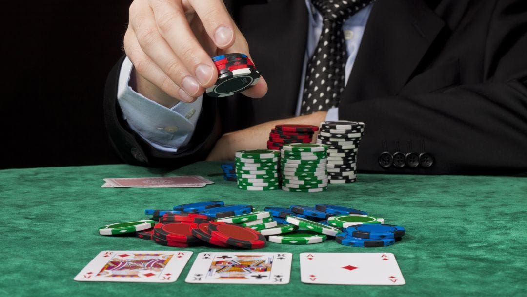 a man is placing a stack of poker chips down on a poker table with playing cards and poker chips on it