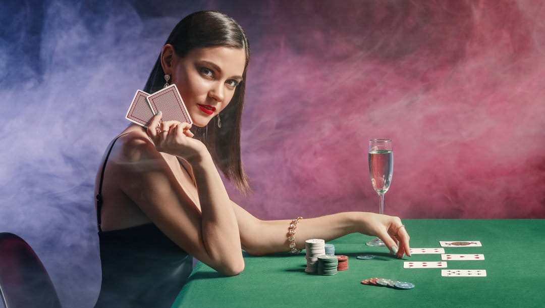 Side-view of a poker player holding their hole cards next to their face.