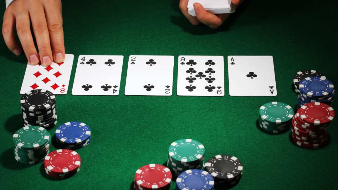 A poker dealer puts a community card down on a table surrounded by poker chips