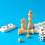 Items for playing chess, poker, and domino on blue background studio shot