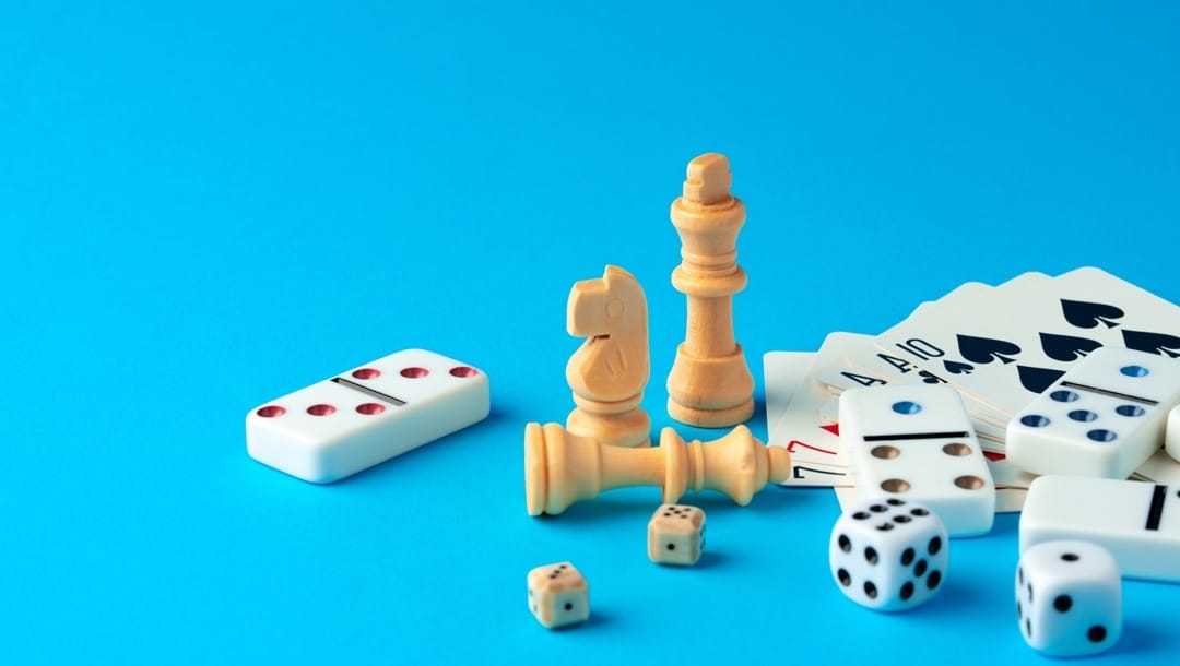 Items for playing chess, poker, and domino on blue background studio shot