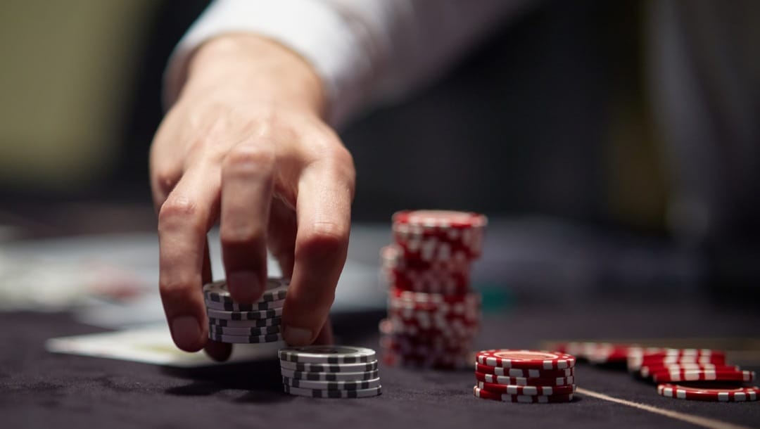 Dealer or croupier shuffles poker cards in a casino on the background of a table