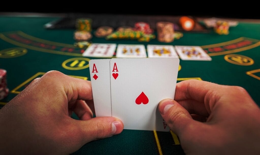 Poker player holding two aces at a green casino table