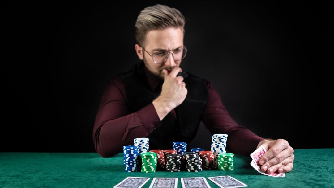 Poker player sitting at a green gaming table with chips and cards