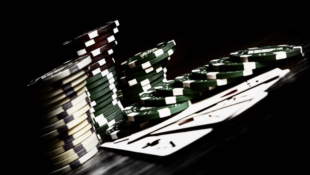 Casino chips and playing cards on a black surface.