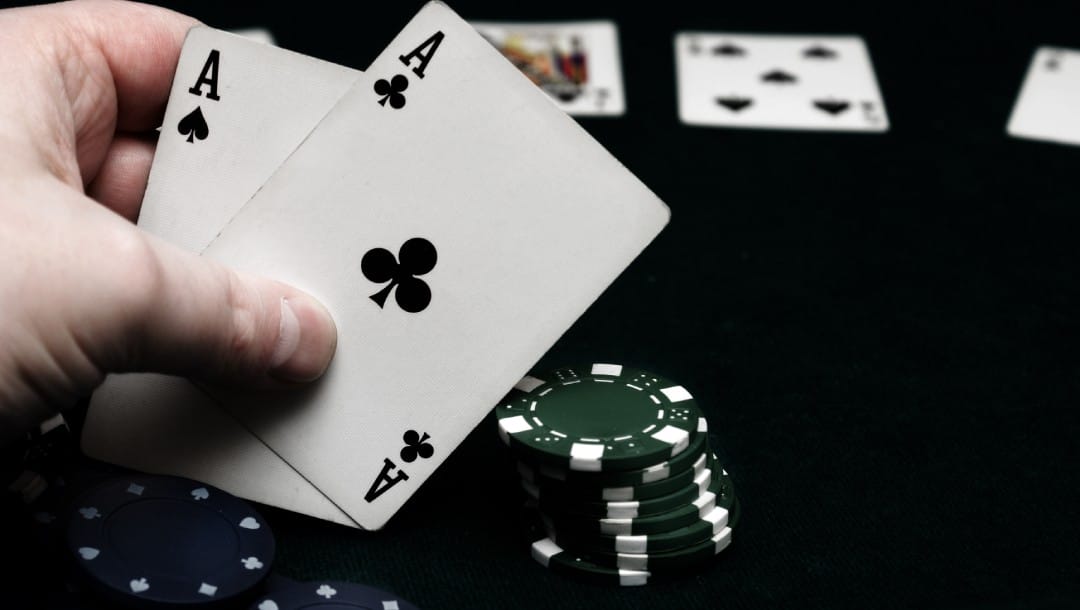 Aces high on top of casino chips on a black table.