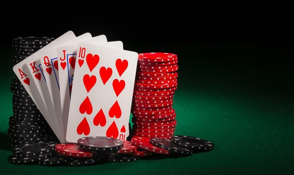 A royal flush leaning against stacks of red and black poker chips.