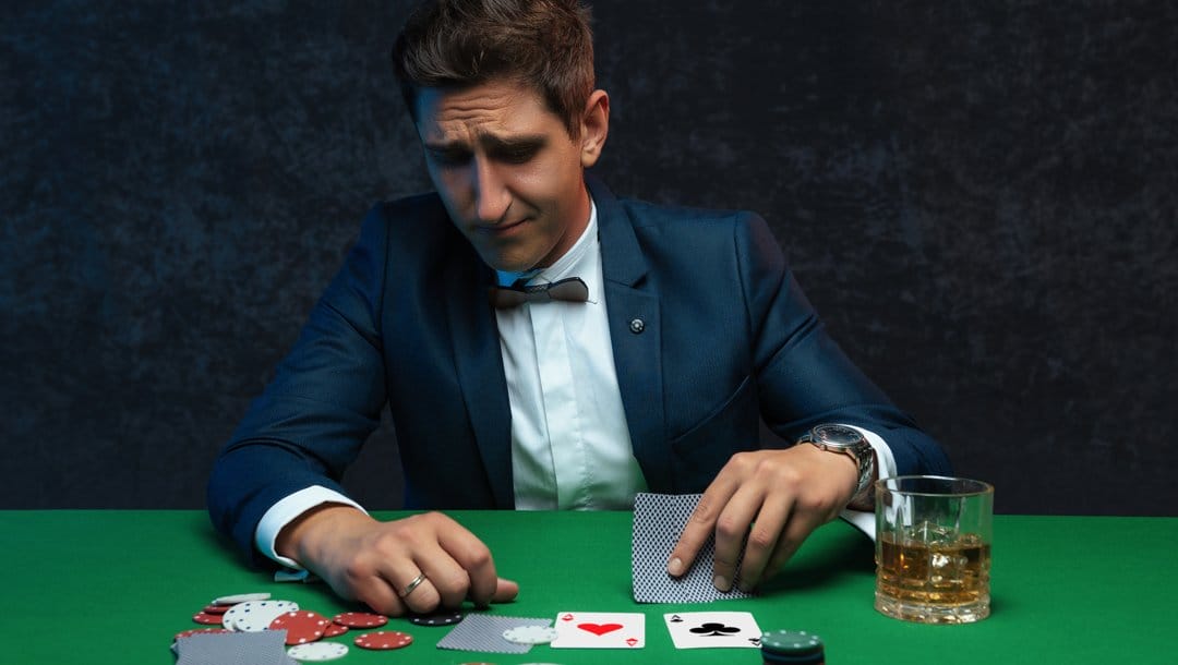 A poker player looks anxiously at their hole cards.