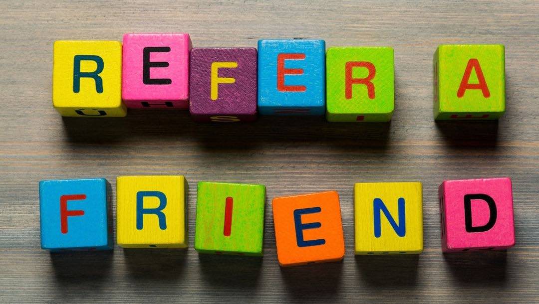 “Refer a friend” written in wooden square letters.