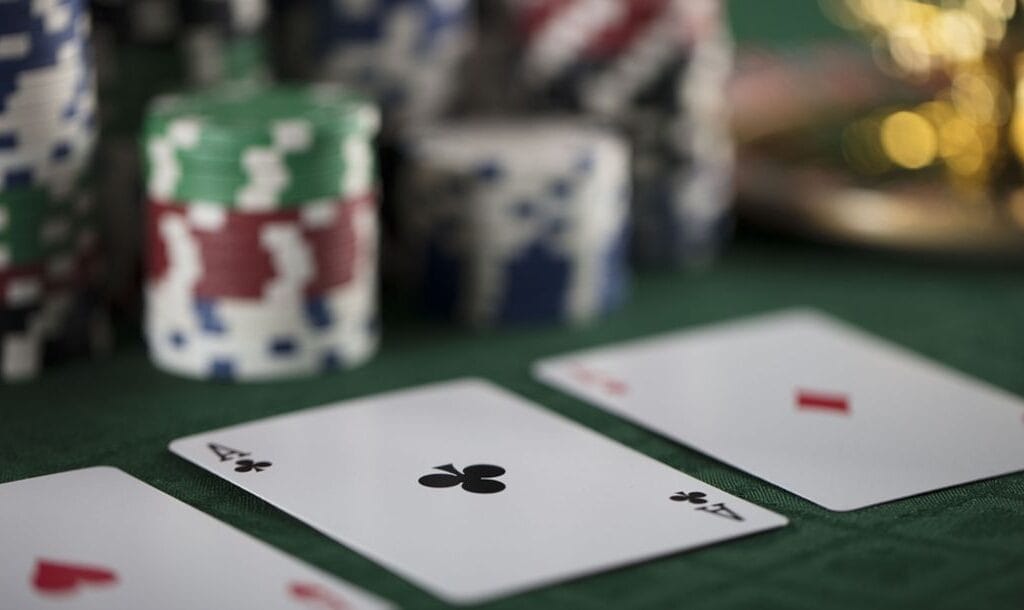Close up of playing cards on a poker table surrounded by stacks of casino chips.