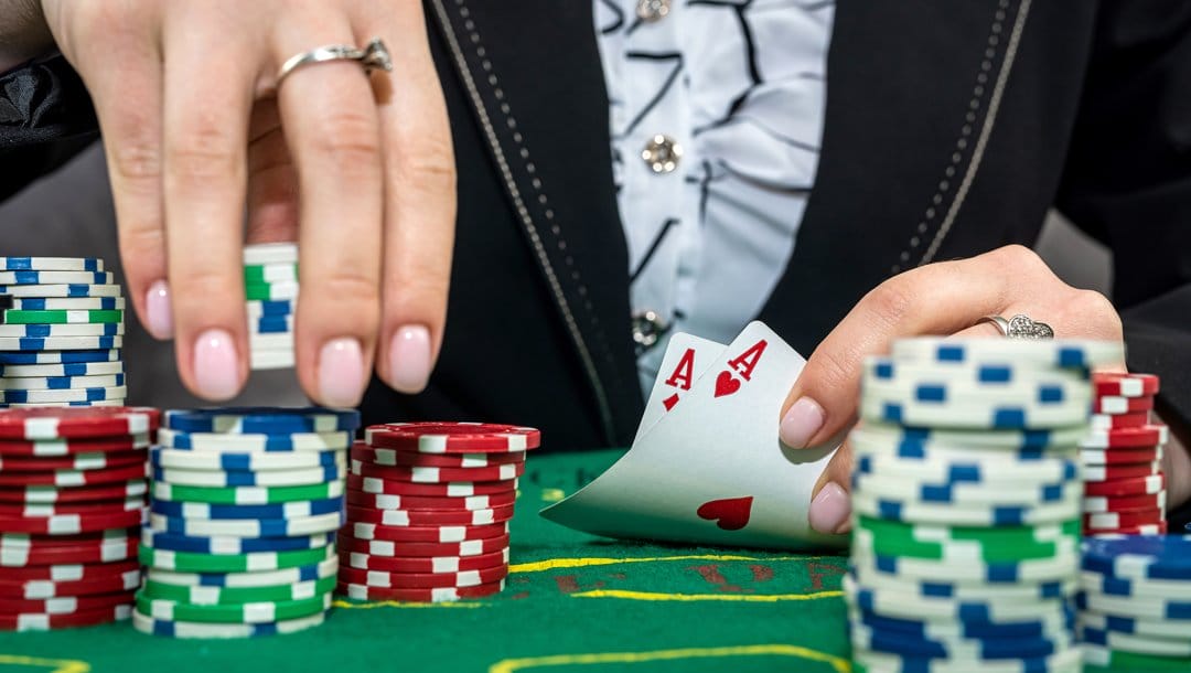 A poker player reveals their hole cards while picking up chips for a bet.