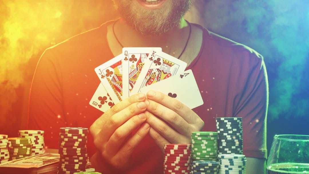 Cropped shot of smiling poker player man showing his cards to the camera