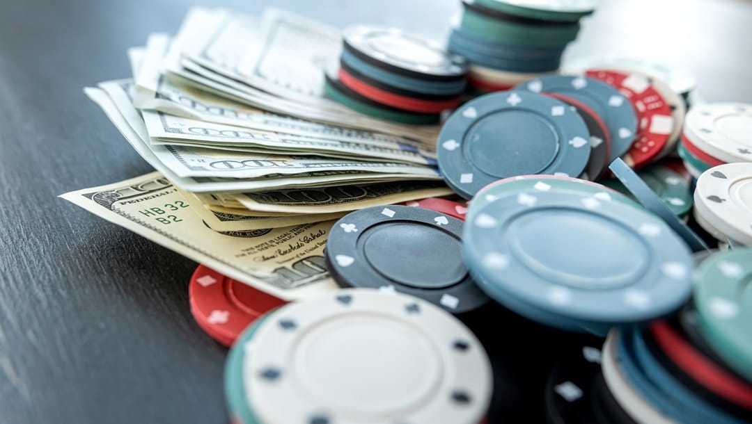 Poker different value chips with dollar bills at black table