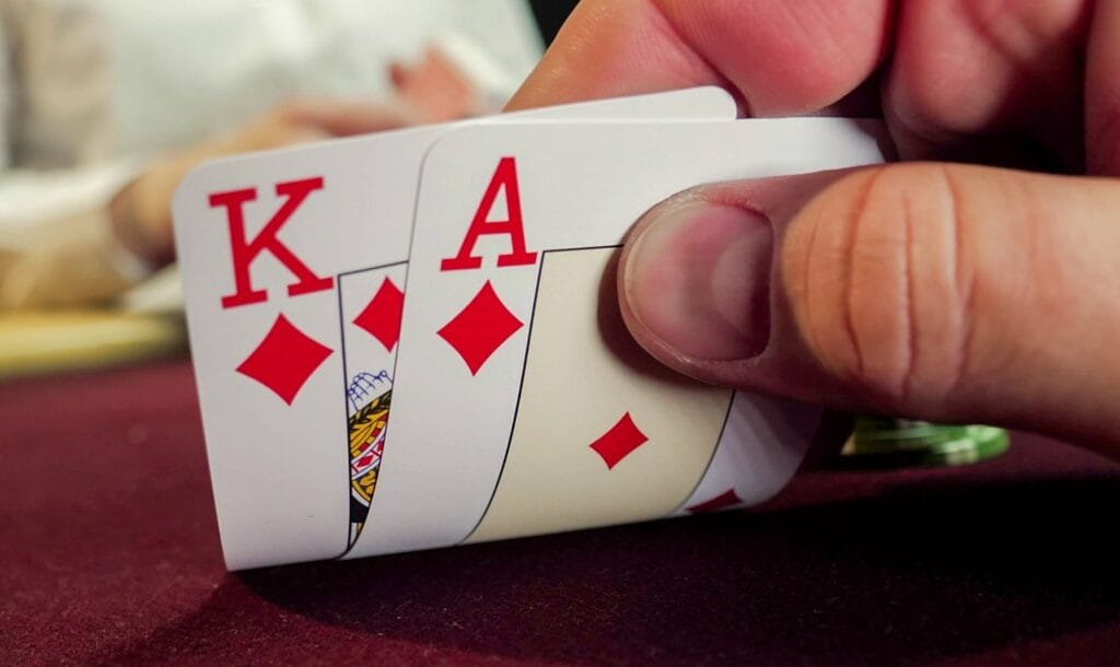 A poker player checks their hole cards — an ace and king of diamonds.