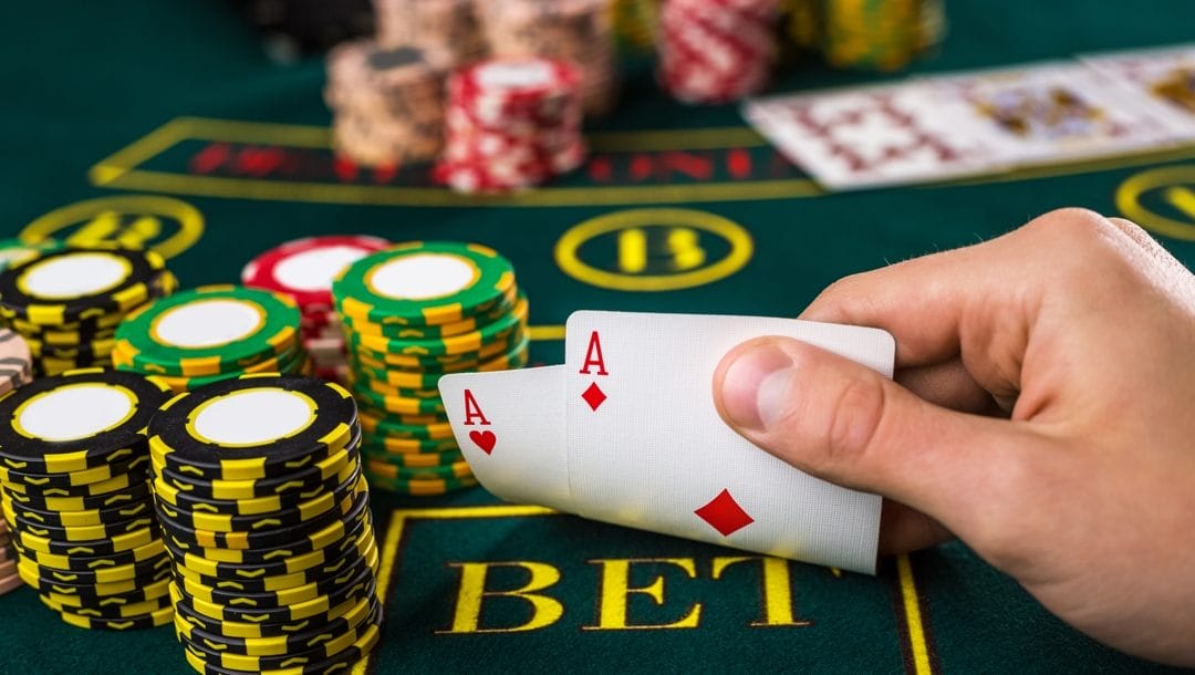 Male poker player lifting the corners of two aces