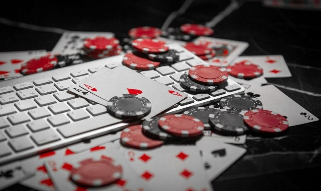 A white keyboard with playing cards and poker chips scattered around.