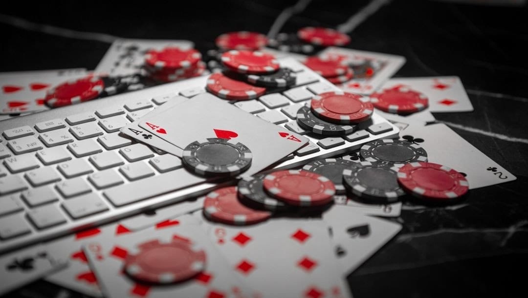 Playing cards and casino chips spread out over a computer keyboard.