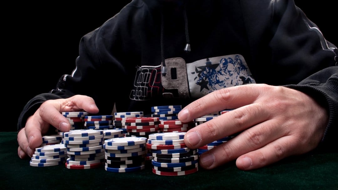 A poker player with their hands around stacks of chips.