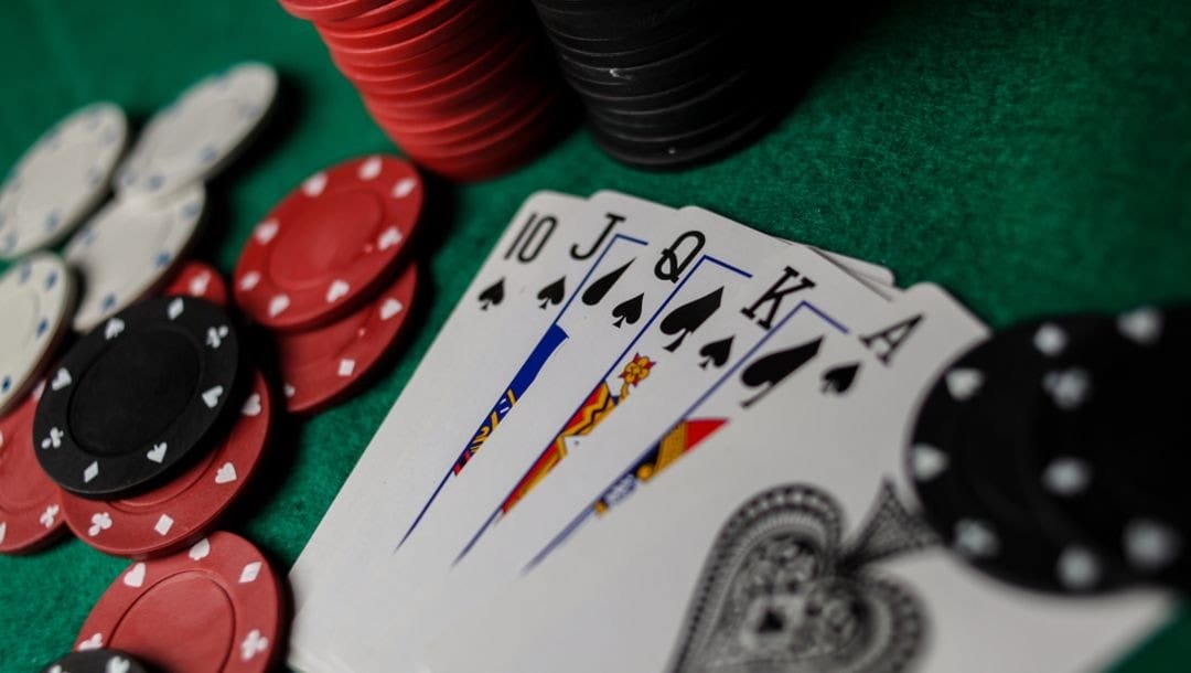 A royal flush spread out on a poker table surrounded by casino chips.