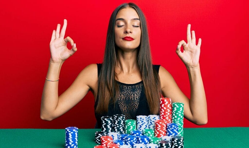 A person meditating in front of stacks of poker chips.