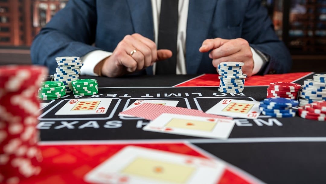 Dealer or croupier shuffles poker cards in a casino on the background of a table with poker chips.