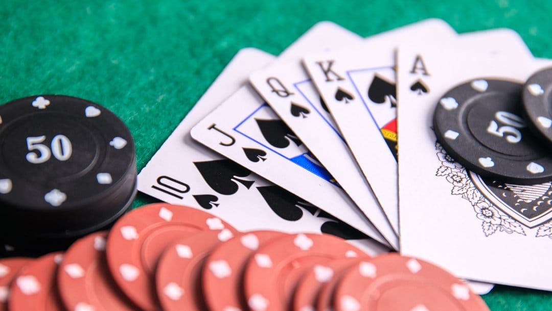 A royal flush face-up on a green casino table next to scattered poker chips.