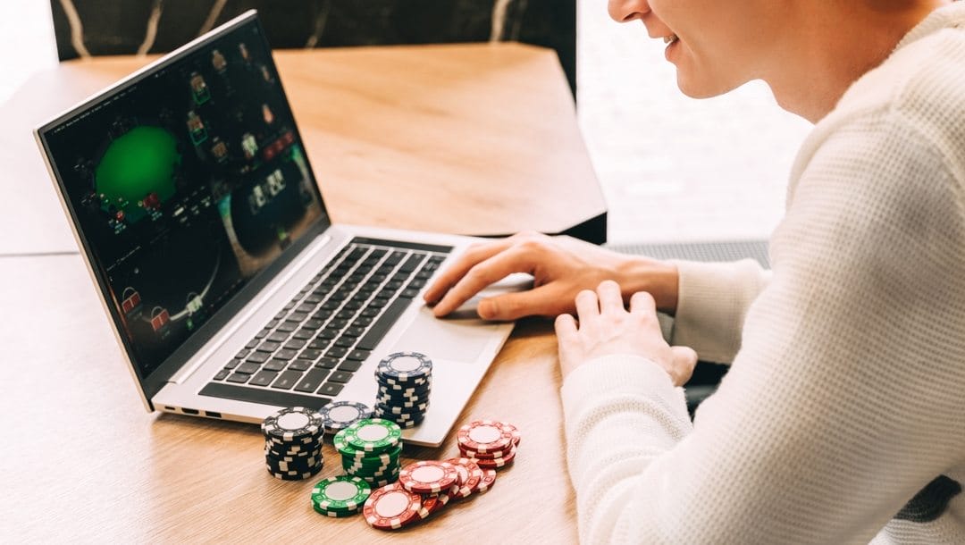 Young man plays online poker on his laptop.