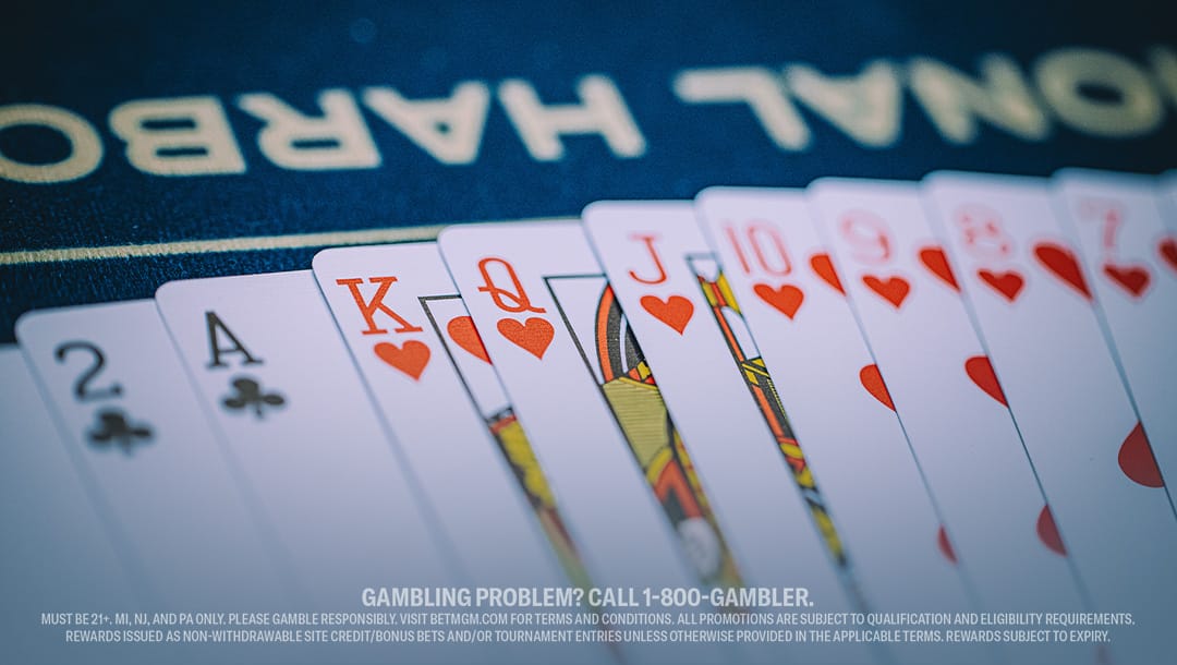 A hand of playing cards featuring a royal flush in hearts, with text at the bottom about responsible gambling. The scene conveys excitement and caution.