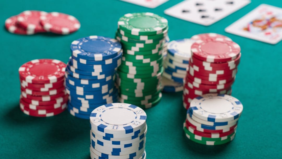 Casino chips and playing cards on a turquoise felt poker table.