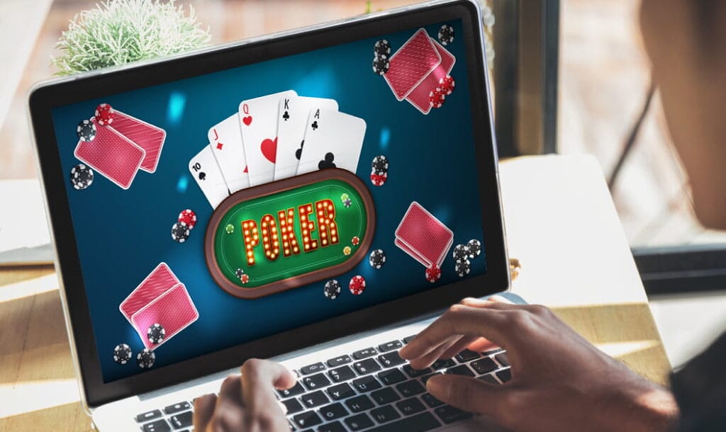 A person sitting at a table, playing an online poker game on a laptop.