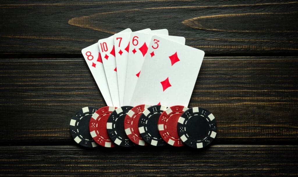 Playing cards with black and red casino chips on a wooden surface.
