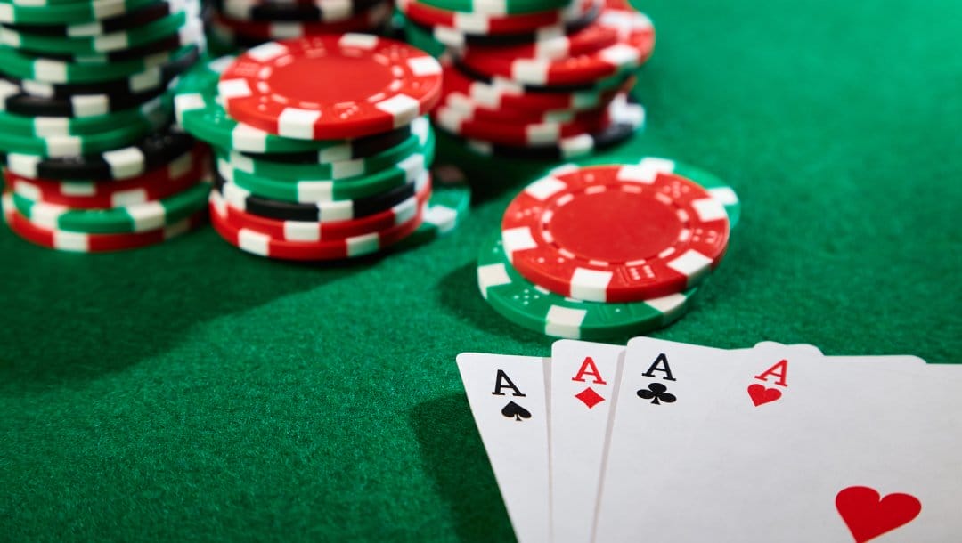 Ace playing cards with green and red casino chips on a green felt table.