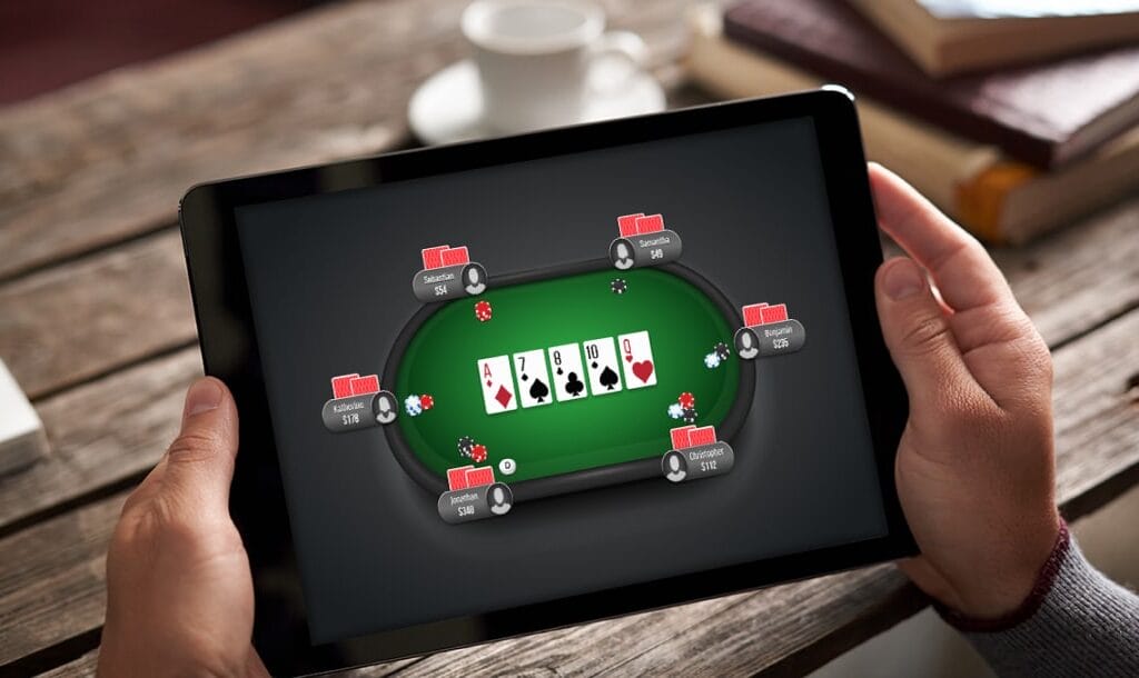 Hands holding a tablet device with an online poker game on the screen.