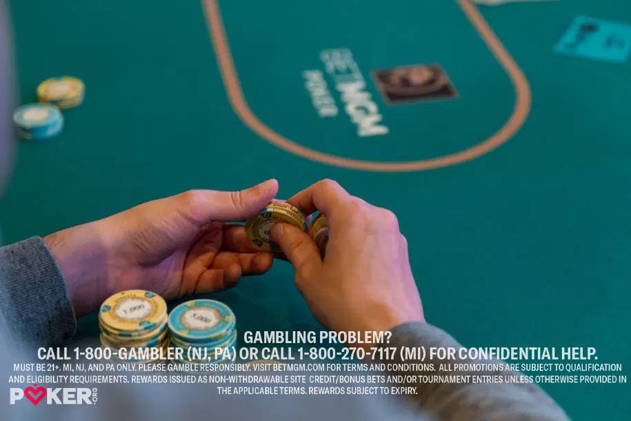 Hands stacking poker chips on a green BetMGM Poker table.