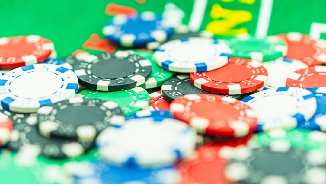Red, green, white, and blue casino chips on a green poker table.